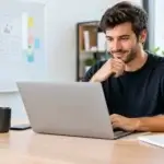 Website design for startup founders: founder working at a laptop, website wireframe sketches on a whiteboard behind