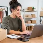 WooCommerce store for small business: owner at a laptop, online store products on a monitor, parcels and a clothes rail
